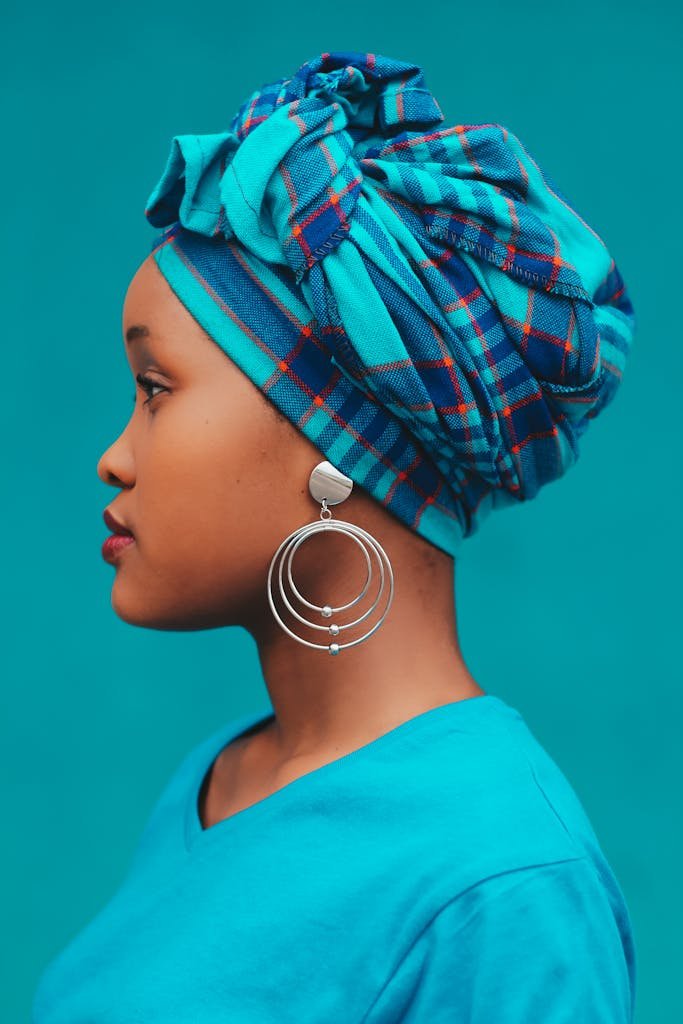 Portrait of a stylish woman in blue headwrap and earrings, showcasing elegance.